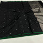 “Black Chanderi cotton silk saree with silver buti motifs and green contrast border, neatly draped and displayed.”