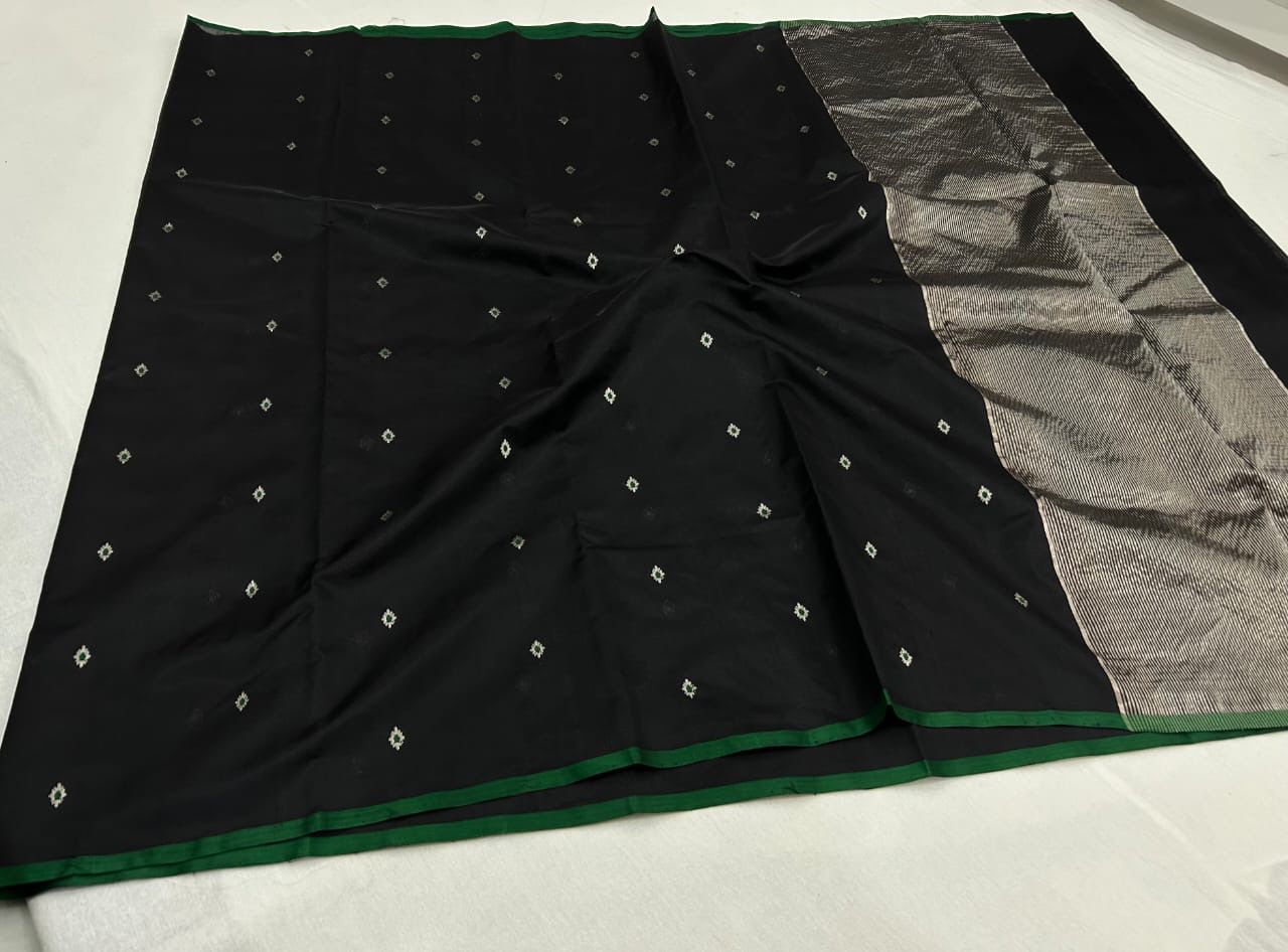 “Black Chanderi cotton silk saree with silver buti motifs and green contrast border, neatly draped and displayed.”